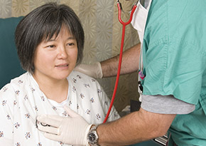 Doctor checking woman's heart beat with a stethoscope
